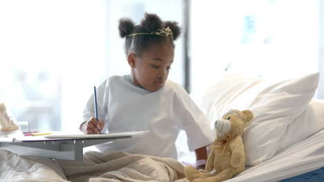African-american-girl-holding-mascot-in-hospital-bed,-slow-motion