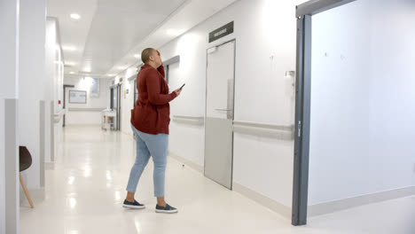 Stressed-african-american-woman-using-smartphone-in-hospital-corridor,-slow-motion