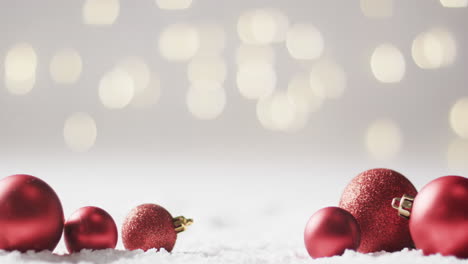 Video-of-red-baubles-christmas-decorations-with-copy-space-on-snow-background
