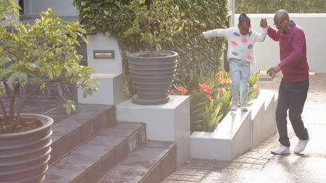 African-american-grandfather-with-granddaughter-jumping-in-sunny-garden,-copy-space,-slow-motion