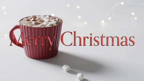 Merry-christmas-text-in-red-over-hot-chocolate-with-marshmallows-on-grey-background