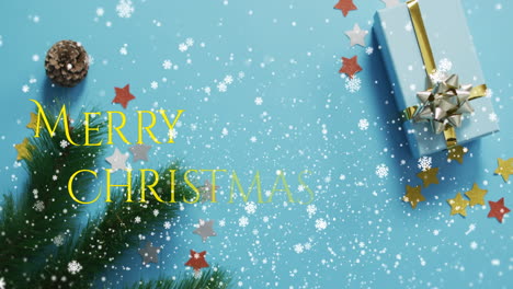 Animation-Von-Schnee,-Der-über-Den-Text-„Frohe-Weihnachten“-Fällt,-Vor-Geschenken-Und-Dekorationen-Auf-Einer-Blauen-Oberfläche