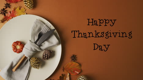Animation-of-happy-thanksgiving-text-and-cutlery-and-pine-cones-over-brown-background