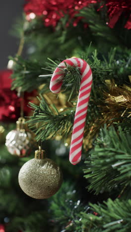 Vertical-video-of-christmas-tree-with-candy-cane-and-decorations-and-copy-space