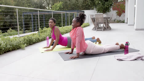 Glückliche-Afroamerikanische-Tochter-Und-Mutter-Praktizieren-Yoga-Im-Garten,-Zeitlupe
