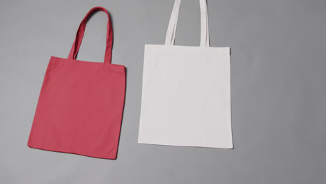 Close-up-of-red-and-white-bags-on-grey-background,-with-copy-space,-slow-motion