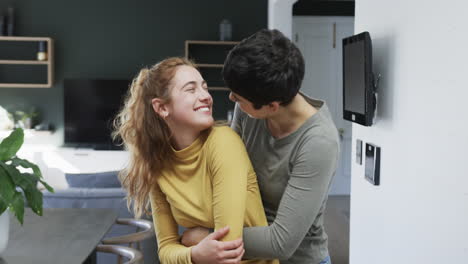 Happy-caucasian-lesbian-couple-embracing,-smiling-and-laughing-in-sunny-kitchen