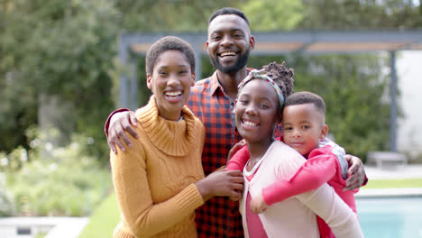 Retrato-De-Felices-Padres-Afroamericanos,-Hijo-E-Hija-Abrazándose-Y-Sonriendo-En-Un-Jardín-Soleado