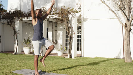 Hombre-Birracial-Enfocado-Practicando-Yoga-En-Un-Jardín-Soleado,-Cámara-Lenta