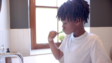 African-american-boy-brushing-teeth-in-bathroom-at-home,-slow-motion