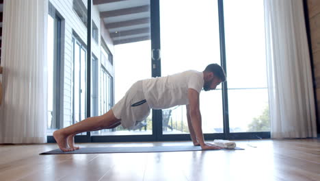 Biracial-man-doing-yoga-and-stretching-at-home,-slow-motion