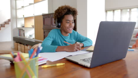 African-american-boy-wearing-headphones,-using-laptop-for-online-class,-slow-motion
