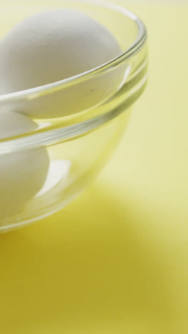 Video-of-close-up-of-glass-bowl-with-eggs-on-yellow-background