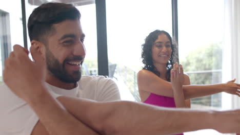 Happy-biracial-couple-doing-yoga-and-stretching-at-home,-in-slow-motion