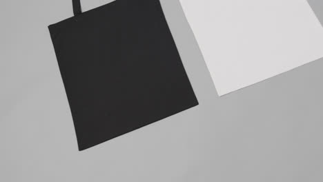 Nahaufnahme-Von-Weißen-Und-Schwarzen-Taschen-Auf-Grauem-Hintergrund,-Mit-Kopierraum,-Zeitlupe