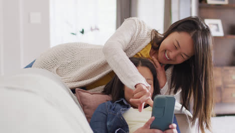 Video-Einer-Glücklichen-Asiatischen-Mutter-Und-Tochter,-Die-Mit-Dem-Smartphone-Auf-Dem-Sofa-Sitzen