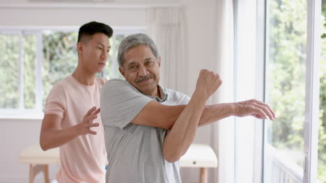 Senior-biracial-man-receives-physical-therapy-at-home,-with-copy-space