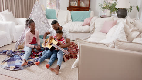 Happy-african-american-father,-son-and-daughter-playing-guitar-in-living-room,-slow-motion