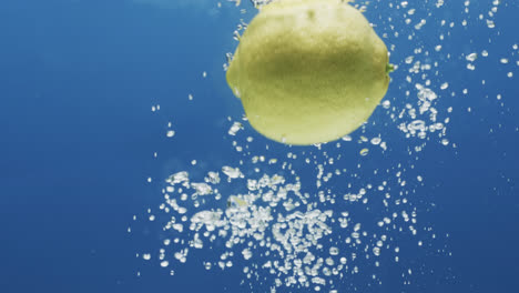 Video-Einer-Zitrone,-Die-Ins-Wasser-Fällt,-Mit-Kopierraum-Auf-Blauem-Hintergrund
