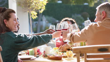 Happy-diverse-male-and-female-friends-toasting-on-celebration-meal-in-sunny-garden