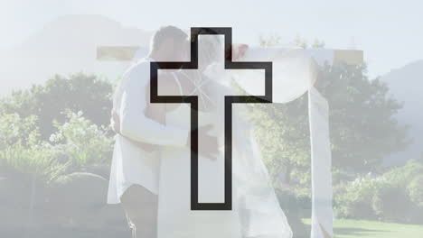 Animation-of-black-outline-crucifix-cross-over-biracial-couple-dancing-at-their-wedding