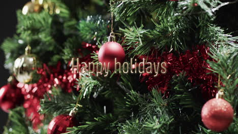 Happy-holidays-text-over-decorations-on-christmas-tree