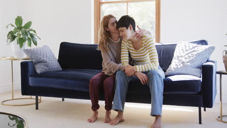 Glückliches-Kaukasisches-Lesbisches-Paar,-Das-Auf-Dem-Sofa-Sitzt,-Sich-Umarmt-Und-Sich-Gegenseitig-In-Einem-Sonnigen-Haus-Unterstützt