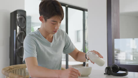 Asian-male-teenager-sitting-at-table-alone-and-having-breakfast