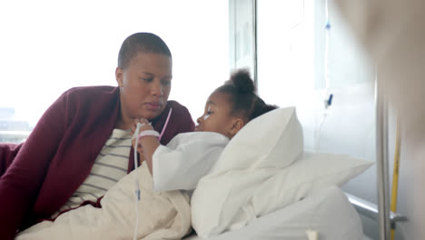 African-american-mother-talking-with-daughter-lying-in-hospital-bed,-slow-motion