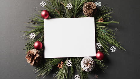 Video-of-christmas-decorations-and-white-card-with-copy-space-on-black-background