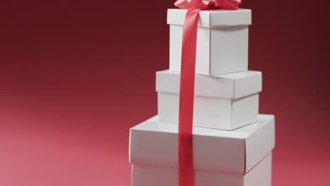 Video-of-stack-of-presents-with-red-ribbon-with-copy-space-on-red-background