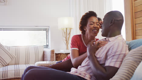 Video-of-happy-african-american-couple-sitting-on-sofa-and-talking