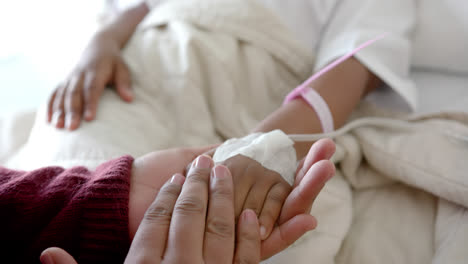 Holding-hands-of-african-american-mother-and-daughter-lying-in-hospital-bed,-slow-motion