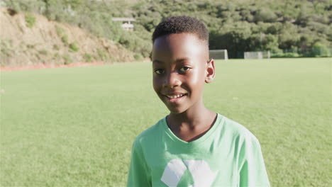Afroamerikanischer-Junge-Lächelt-Auf-Einem-Sonnigen-Feld-Im-Freien-Und-Trägt-Ein-Grünes-Recycling-T-Shirt