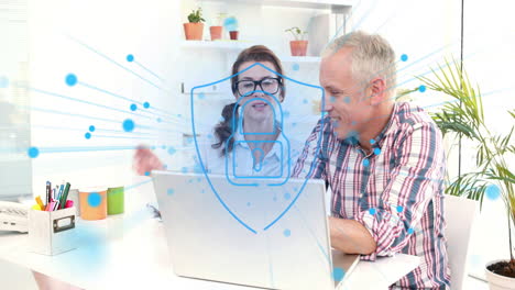 Animation-of-security-padlock-icon-against-diverse-man-and-woman-discussing-over-a-laptop-at-office