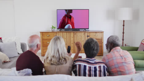 Senior-diverse-friends-watching-tv-with-african-american-male-rugby-player-with-ball-on-screen