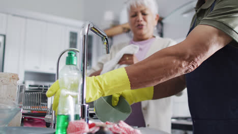 Happy-senior-biracial-couple-washing-dishes-in-kitchen