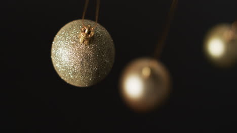 Video-of-gold-baubles-christmas-decorations-with-copy-space-on-black-background