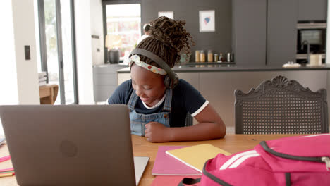 Glückliches-Afroamerikanisches-Mädchen-Mit-Kopfhörern-Und-Laptop,-Das-Im-Online-Unterricht-Die-Hand-Hebt,-Zeitlupe