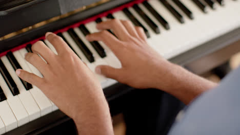 Close-up-of-hands-of-biracial-man-playing-piano-at-home,-slow-motion