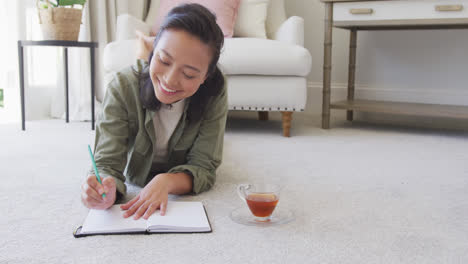 Happy-asian-woman-taking-notes-in-bedroom,-in-slow-motion