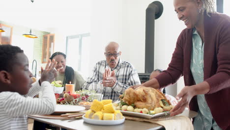 Fröhliche-Afroamerikanische-Mehrgenerationenfamilie,-Die-Essen-Beim-Thanksgiving-Dinner-Serviert,-Zeitlupe