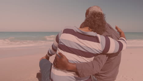 Rear-view-of-african-american-couple-hugging-each-other-while-sitting-at-the-beach