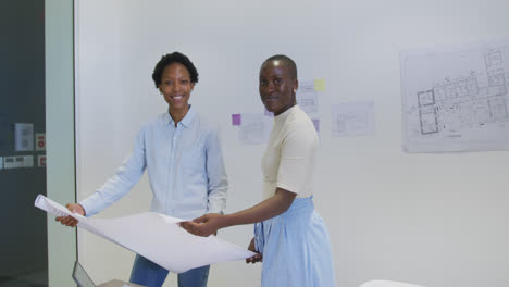Retrato-De-Dos-Felices-Arquitectas-Afroamericanas-En-Discusión-Estudiando-Planos-En-La-Oficina