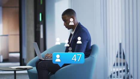 Animation-of-message-icons-with-increasing-numbers-over-african-american-man-using-laptop-at-office