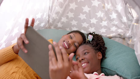 Happy-african-american-mother-and-daughter-using-tablet-and-smiling-at-home,-slow-motion
