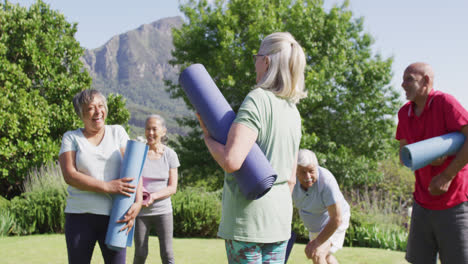 Diverse-group-of-happy-male-and-female-seniors-talking-after-exercising-in-garden,-slow-motion
