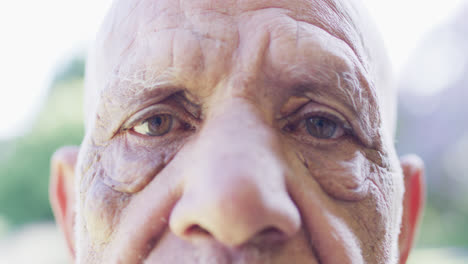 Portrait-of-close-up-of-senior-biracial-man-opening-eyes-wide-in-garden,-in-slow-motion