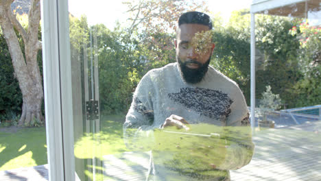 African-american-man-using-tablet-in-sunny-living-room,-slow-motion