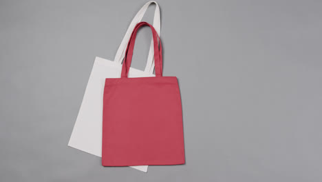 Close-up-of-white-and-red-bags-on-grey-background,-with-copy-space,-slow-motion